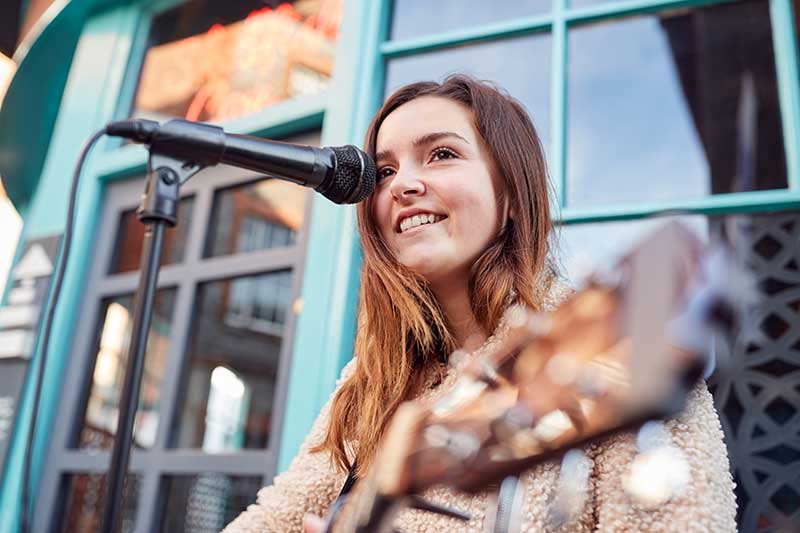 female-musician-busking-playing-acoustic-guitar-QGPZ2UP.jpg